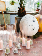 Powder-colored candles in high glass vases stand on the ground. Party decor.
