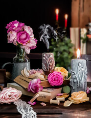 Burning candles and flowers on table against black background