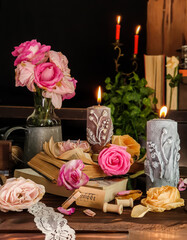 Burning candles and flowers on table against black background