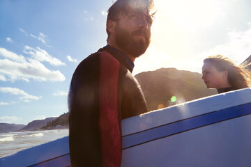 Lets do this. an athletic young couple surfing at their favourite beach.