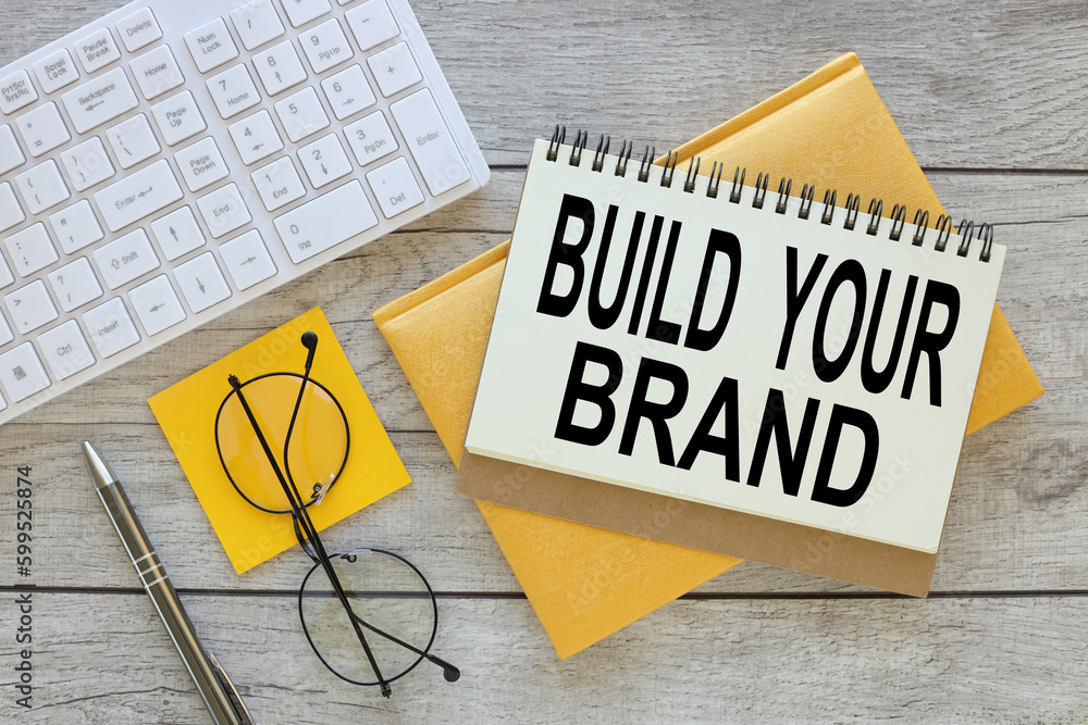 Poster build your brand text. open notepad with text. two notepads near white keyboard