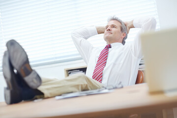 Putting my feet up after a long day. Mature, attractive businessman relaxing in an office chair.