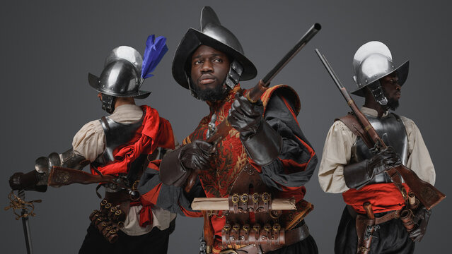 Portrait of multiethnic group of three conquistadors with steel armors and flintlock rifles.