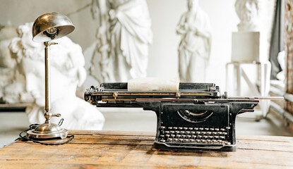 Stylish in the office of a creative person, an old typewriter stands on an old wooden table. The workplace of a writer or journalist.