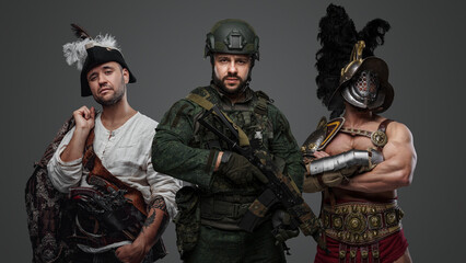 Studio shot of modern soldier with camouflage uniform with aribbean pirate and greek gladiator.
