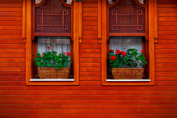 Fototapeta na wymiar Windows and flowers. Wooden house wall