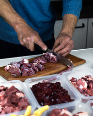 A man prepares various raw meats, bones and offal for freezing. BARF Biologically Appropriate Raw Food for Dogs and Cats. Animal food packaging.