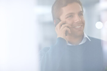 Another client pleased with his work. Through the glass shot of a young office worker talking on his cellphone.