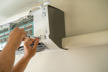 Male professional technician fixing An electrician repairs an air conditioner indoors. removing air filter repairing hot temperatures