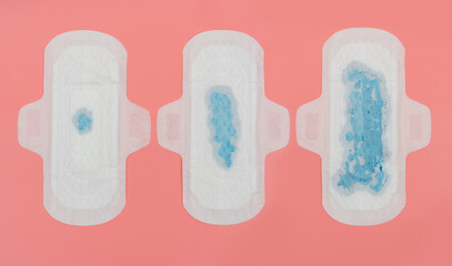 different used sanitary pad on pink background, top-view.