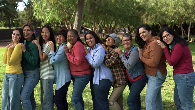 Group of diverse multi generational women smiling on camera at city park
