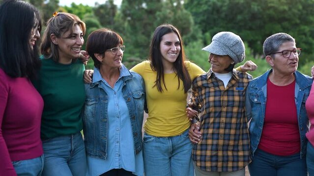 Group of multi generational women hugging each other while smiling in front of camera - Diverse women concept
