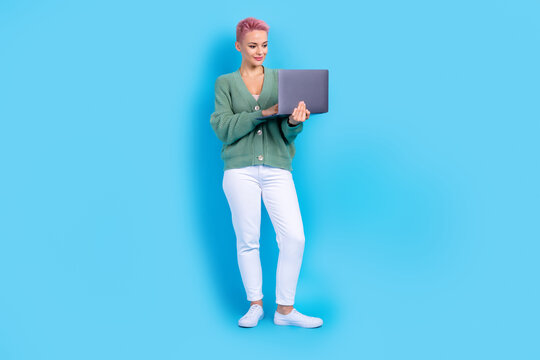Full body photo of young satisfied business blogger pink hair woman writing own book using her laptop isolated on blue color background