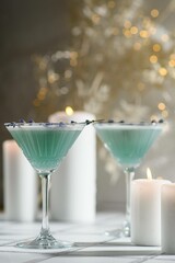 Drink or alcoholic cocktail surrounded by candles in the background with shimmering light