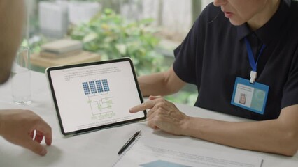 Over the shoulder cropped shot of female engineer discussing solar power project on digital tablet with male colleague during meeting in office - Powered by Adobe