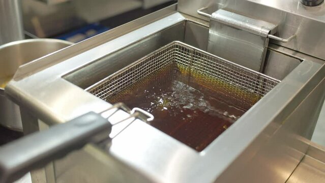 Cooking oil boiling and bubbling in fryer for deep frying dishes in a professional restaurant kitchen, extremely hot