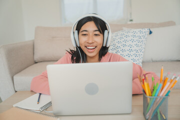 Portrait. Asian girl student learning online with tutor on laptop with headphone 