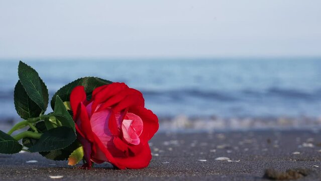 Artificial rose flower made of fabric lies against waves