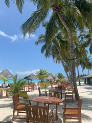 A day in the Maldives, an open restaurant among palm trees, almost without people, next to the beach on the Indian Ocean