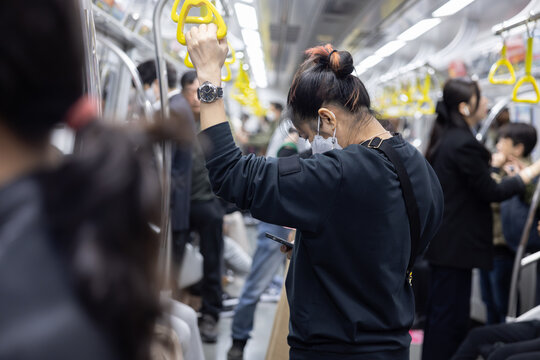 Woman Using Mobilephone inside Crowded Subway Train