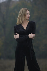 Outdoor portrait of woman in black velvet jumpsuit in the city, fall fashion collection