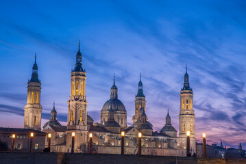 Fototapeta premium del Pilar basilica, one of the important architectural symbols of zaragoza, and the Ebro river and its reflection with sunset colors and clouds