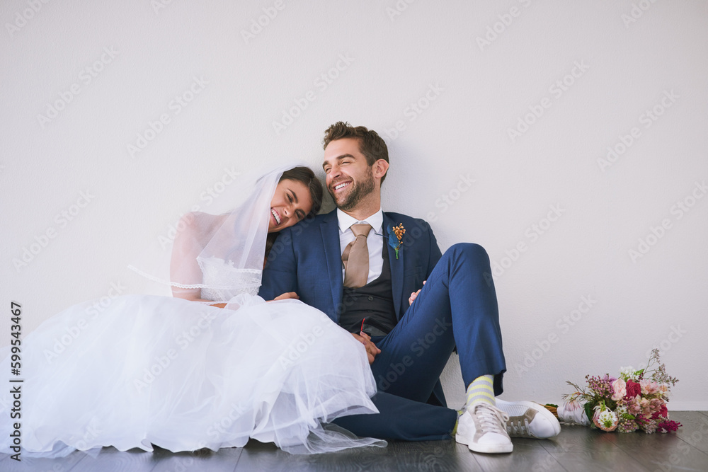 Wall mural The ultimate union. Studio shot of a newly married young couple sitting together on the floor against a gray background.