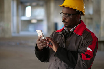 African american workman with smartphone at construction site