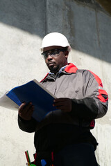 African american worker stands at construction site with work papers