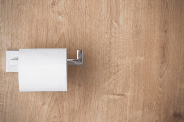 new toilet tissue on chrome holder at wood background