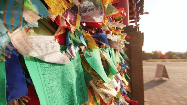 Small flags with Buddhist symbols and mantras are tied to the fence and flutter in the wind
