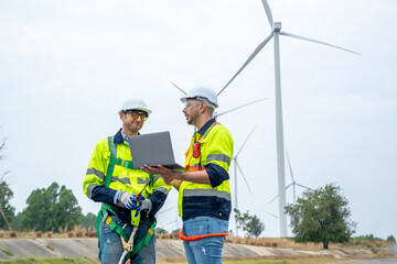 Engineer with technician are inspection work in wind turbine farms rotation to generate electricity energy.