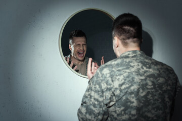 Angry military veteran screaming near mirror while suffering post traumatic stress disorder.