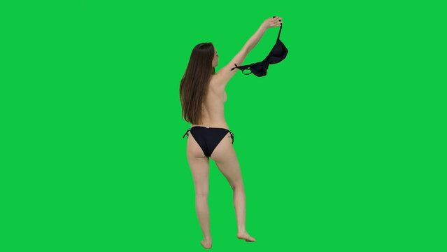 Back side of a Caucasian model taking her bikini top of in front of a green screen