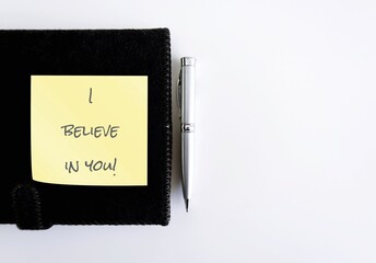 Pen on notebook with handwritten text note - I believe in you! - supporttive phrase to encourahe...