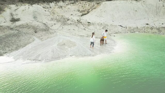 Two children and a dog exploring the shore of a lake in a kaolin quarry