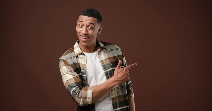 Smiling Amazed Young african american man pointing with index finger to the side