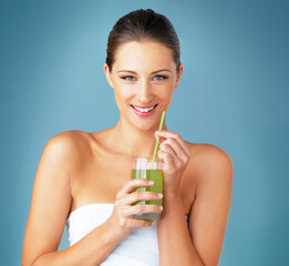 Fototapeta premium Have you tried the new juice diet. Studio portrait of a beautiful young woman drinking a healthy green beverage against a blue background.
