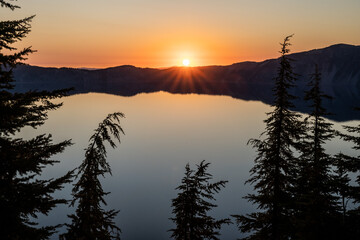 Fototapeta na wymiar Thin Pine Tree Tops Droop From Weight At Sunset Over Crater Lake