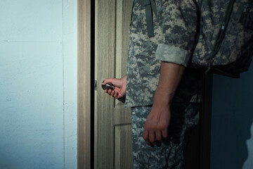 cropped view of serviceman in camouflage opening home door.