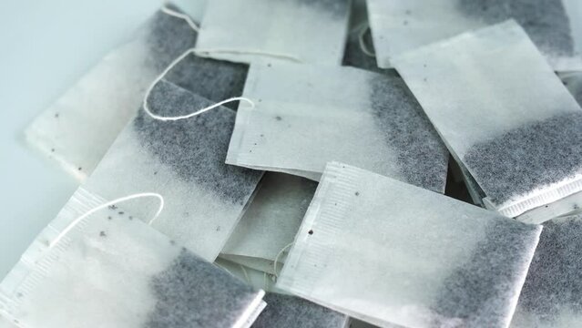 Motion around white tray with large pile of black tea bags