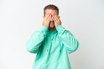 Young handsome caucasian man isolated on white background covering eyes by hands