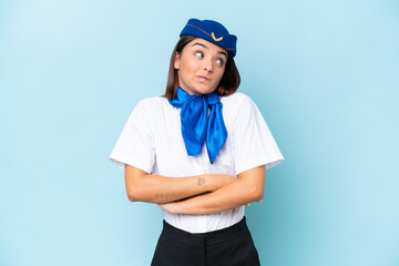 Airplane stewardess caucasian woman isolated on blue background making doubts gesture while lifting the shoulders