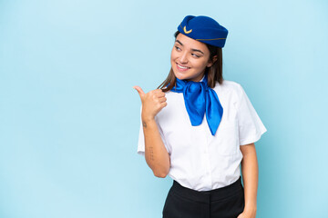 Airplane stewardess caucasian woman isolated on blue background pointing to the side to present a product