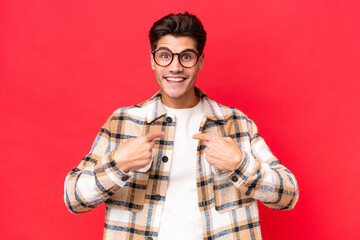 Young caucasian handsome man isolated on red background with surprise facial expression
