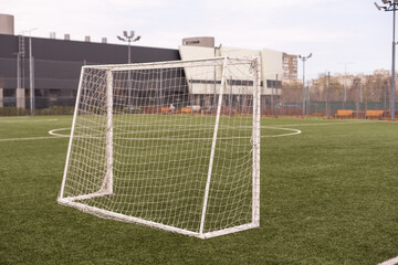 Naklejka premium Football or soccer goal post on a green grass pitch in a park. Nobody. Calm mood. Sport theme background. Training ground for outdoor activity