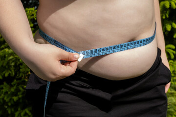 fat woman in black sweater measures waist circumference with centimeter tape, belly stands, concept...