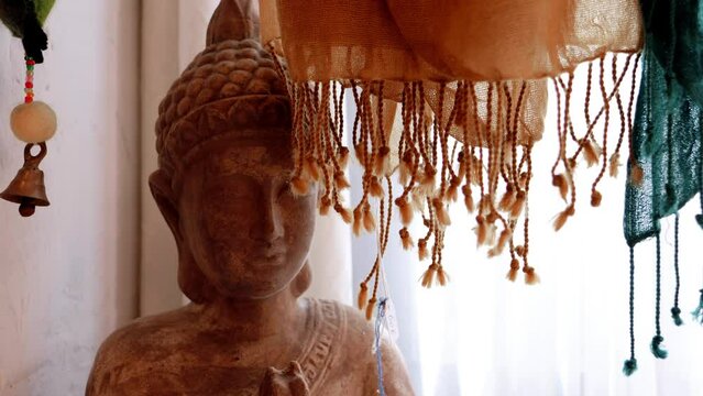 A Spiritual Moment: Woman Reading a Red Book in Front of Colorful Scarf-Adorned Buddha Statue