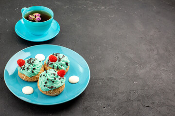 front view little creamy cakes delicious sweets with cup of tea on dark background tea cream cake biscuit dessert color