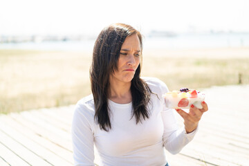Middle aged woman holding a bowl of fruit at outdoors with sad expression